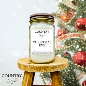 Christmas Eve 16oz candle by Country Wyx on a wooden stool with a blurred Christmas tree and ornaments in the background.