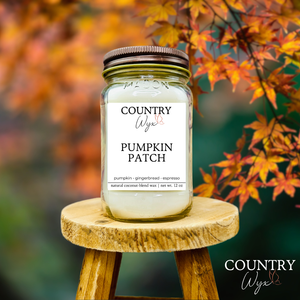 Pumpkin Patch 16oz candle by Country Wyx on a wooden stool with autumn leaves in the background