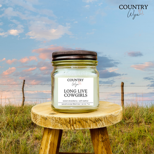 Long Live Cowgirls 8oz candle by Country Wyx on a wooden stool with a Nebraska Sandhills background