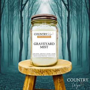Graveyard Mist 16oz candle by Country Wyx on a wooden stool with a spooky forest background