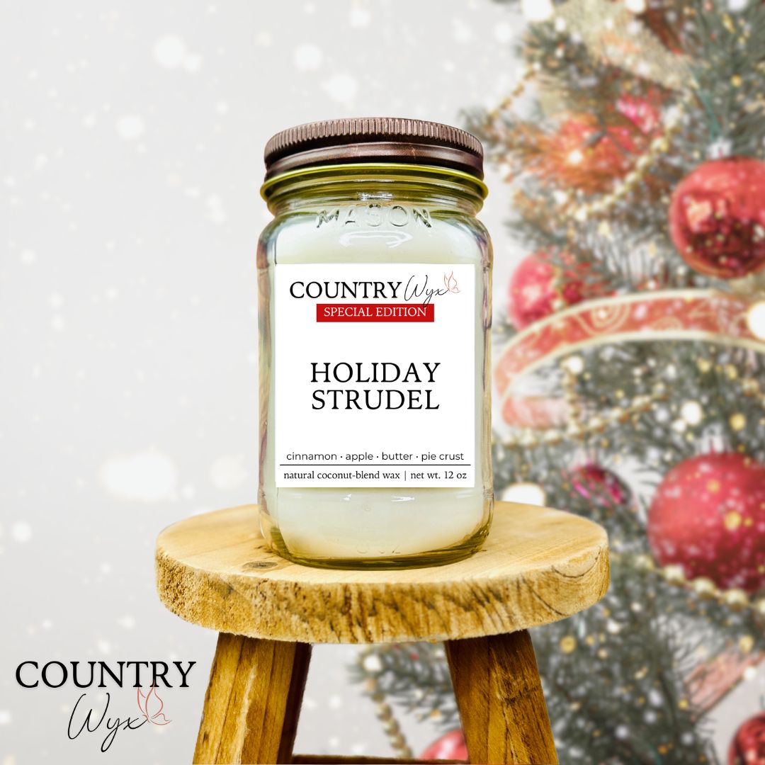 Country Wyx 16oz Holiday Strudel mason jar candle on a wooden stool with a Christmas tree in the background.