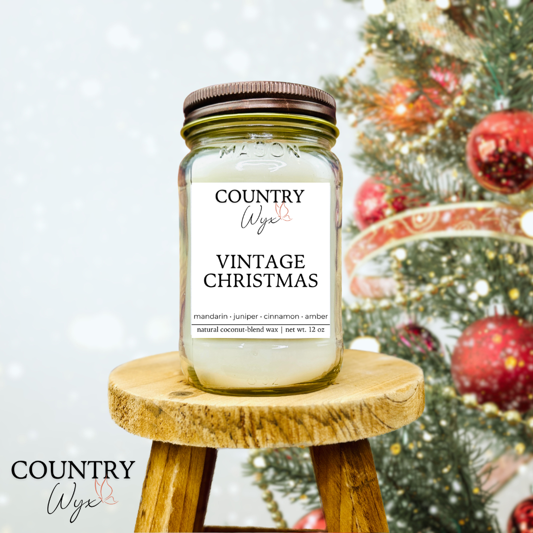 Vintage Christmas 16oz candle by Country Wyx on a wooden stool with a blurred Christmas tree and ornaments in the background.