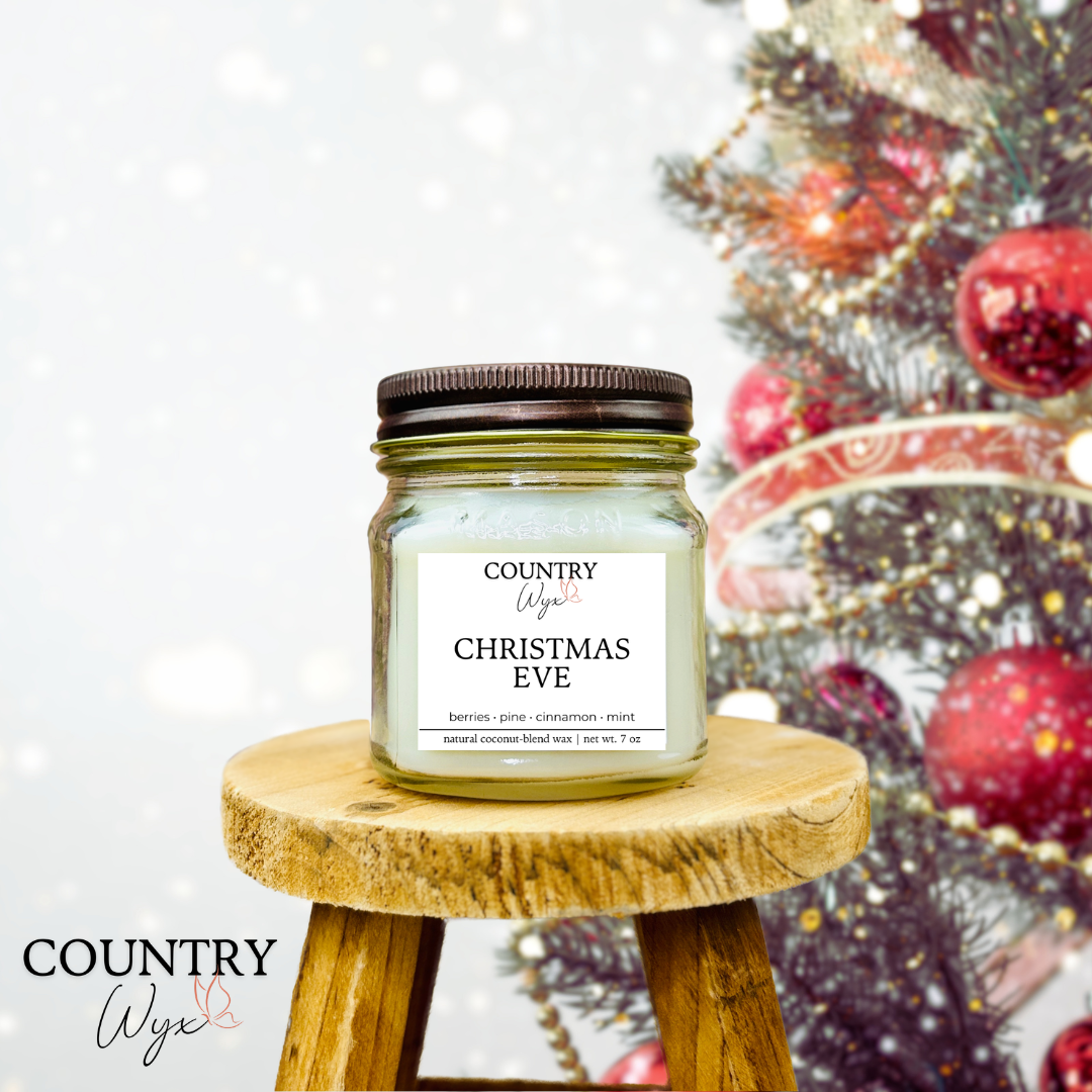 Christmas Eve 8oz candle by Country Wyx on a wooden stool with a blurred Christmas tree and ornaments in the background.