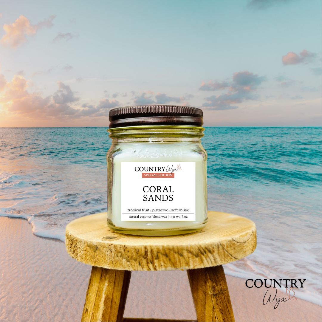 Coral Sands 8oz candle by Country Wyx on a wooden stool with a beach background