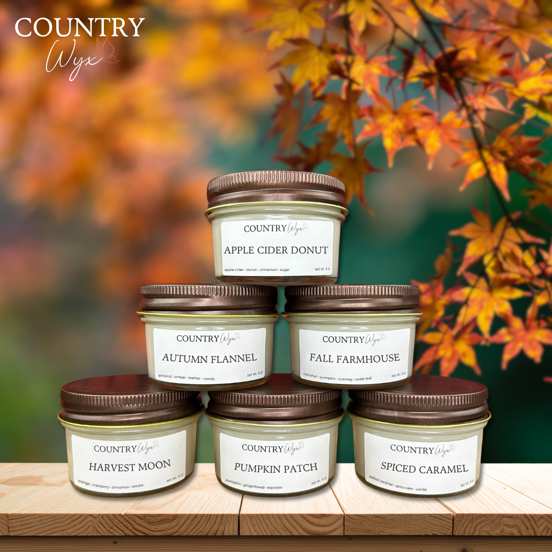 Fall Sample Pack of Country Wyx 4oz candles with autumn-themed labels on a wooden stand against an autumn leaf background