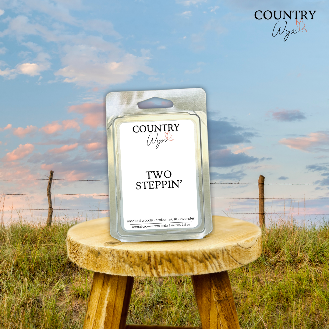 Two Steppin' wax melt by Country Wyx on a wooden stool with a Nebraska Sandhills background