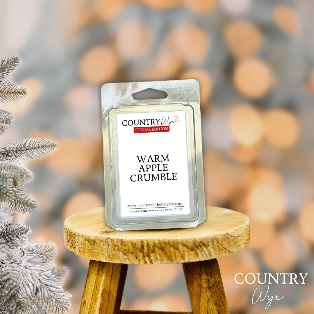 Warm Apple Crumble wax melt by Country Wyx on a wooden stool with a frosted pine tree holiday background